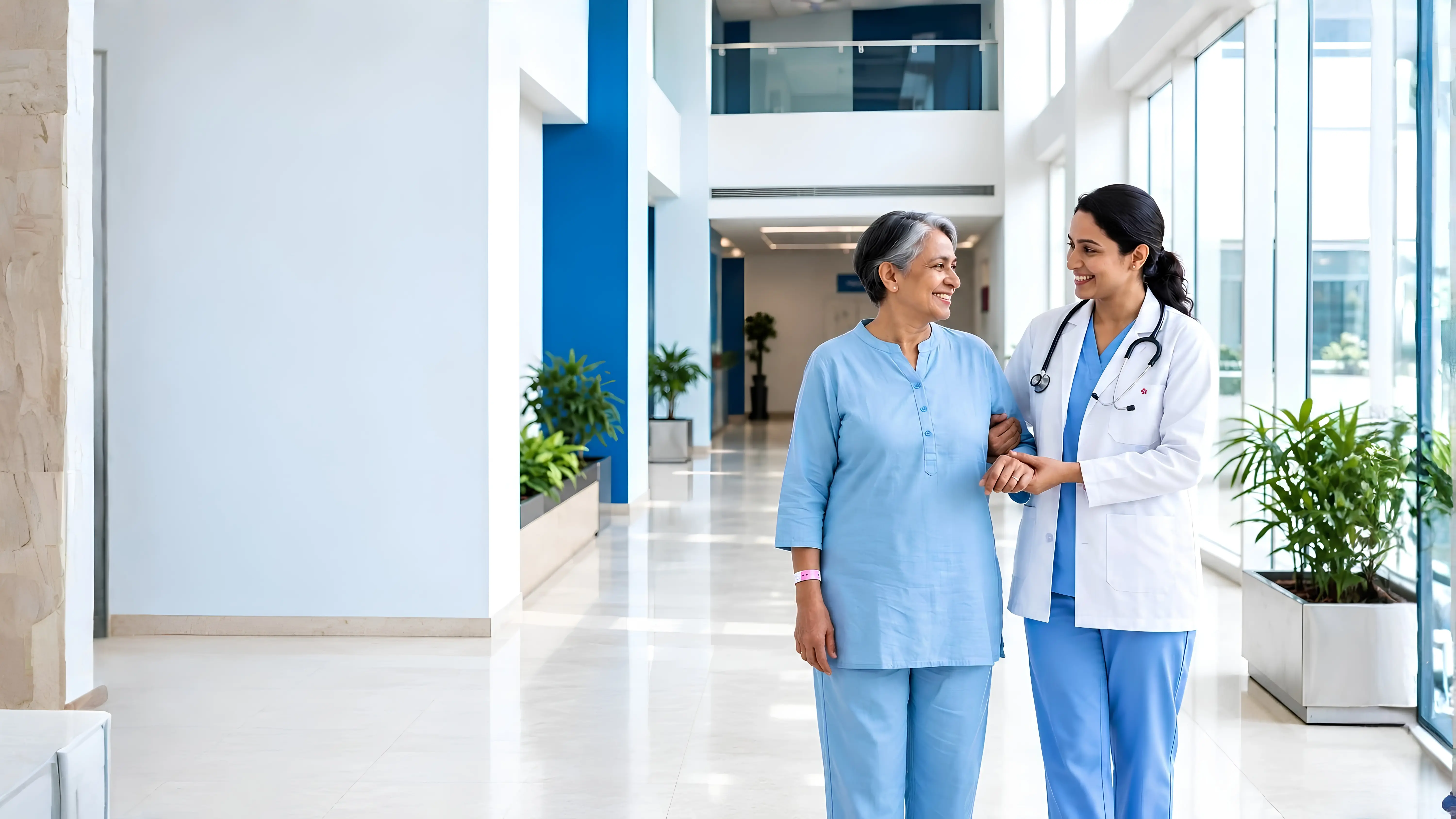 A doctor gently supporting an older patient in a bright hospital corridor